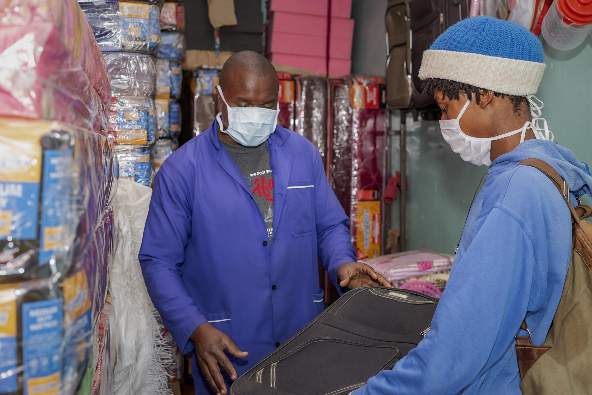 Masked buyer and seller at a shop in Nairobi, Kenya. Photo: World Bank, Sambrian Mbaabu